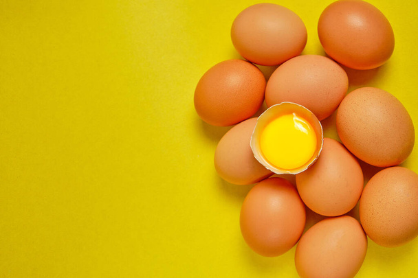 Chicken eggs on a yellow background with yolk - Foto, afbeelding