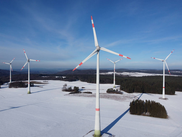 Kışın bir rüzgar çiftliğinin havadan görünüşü. Almanya 'da karlı bir arazide rüzgar türbinlerinin hava görüntüsü. - Fotoğraf, Görsel
