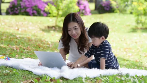 Ευτυχισμένη ασιατική οικογένεια διασκεδάζοντας μητέρα και ο γιος της χρησιμοποιώντας φορητό υπολογιστή στο πάρκο μαζί - Πλάνα, βίντεο