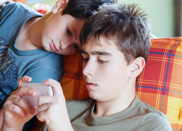 Мальчики-подростки играют на смартфоне, на открытом воздухе
 - Фото, изображение