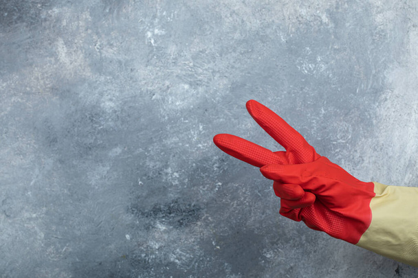 Female wearing red protective gloves on marble background - Photo, Image