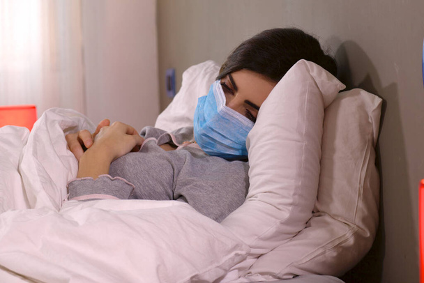 Woman with coronavirus sick lying in hospital bed with protection mask - Foto, immagini