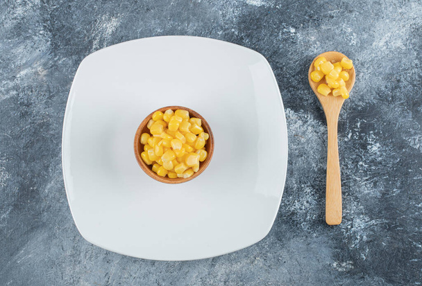 Un cuenco de palomitas de maíz en un plato vacío - Foto, imagen