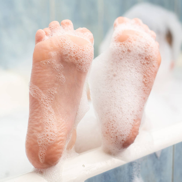 Baby feet in the foam in the bath. Hygiene, cleanliness concept. - Fotografie, Obrázek