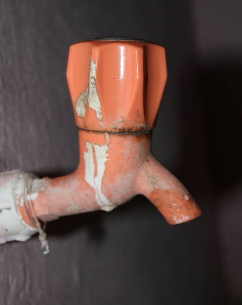vieux robinet en plastique dans la salle de bain avec fond bleu.robinet de couleur orange - Photo, image