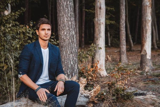 Handsome man posing outdoors in forest wearing checked jacket. Place for text or advertising. - Photo, Image