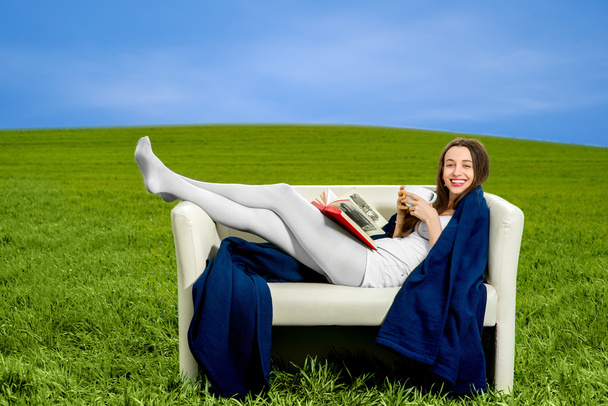 dziewczyna czytanie książki i picie kawy na kanapie w kolorze zielonym  - Zdjęcie, obraz