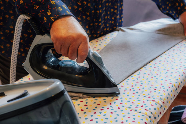 Großaufnahme einer Frau, die ein Hemd bügelt. Hausarbeit. - Foto, Bild