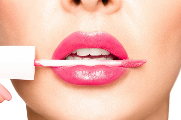 Labios de niña con lápiz labial rosa. En la boca, un aplicador para aplicar lápiz labial.. - Foto, Imagen