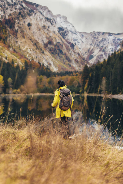バックパックとレインコートのハイキングを持つ女性野生への積極的な休暇を背景にライフスタイルアドベンチャーコンセプトの森と湖 - 写真・画像