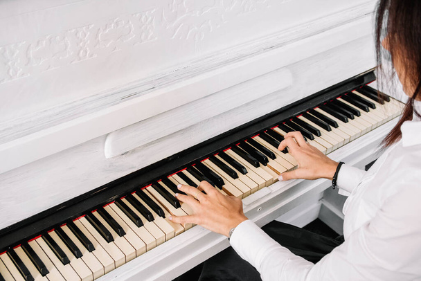 Schöne Frau in weißem Kleid spielt auf weißem Klavier. - Foto, Bild