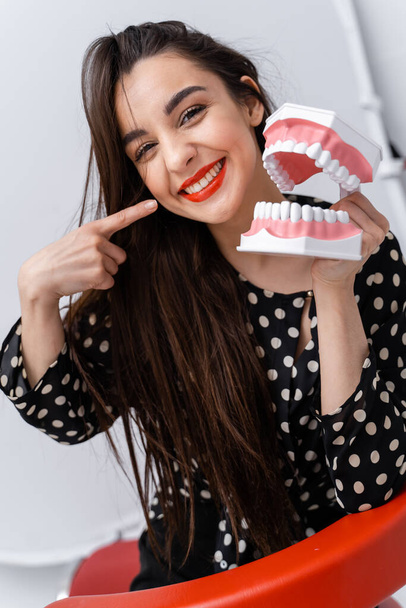Mujer sosteniendo modelo educativo de cavidad oral con dientes sobre fondo blanco. Emociones y expresiones divertidas. - Foto, imagen