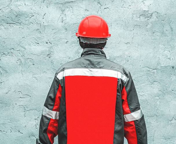 Рабочий в красном шлеме. серый костюм с красным - Фото, изображение