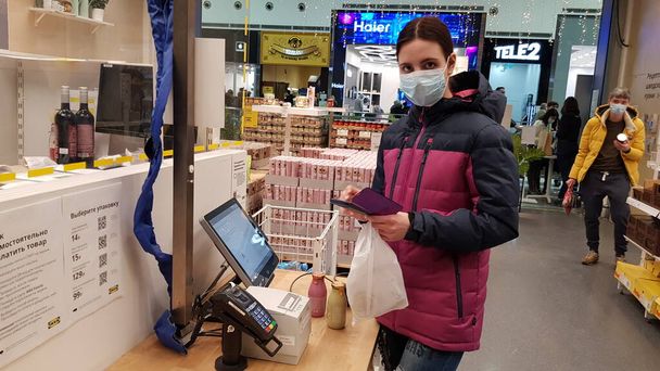 Russia, St. Petersburg 02.01.2021 Buyer in a mask at a self-checkout counter during the coronavirus epidemic - Valokuva, kuva