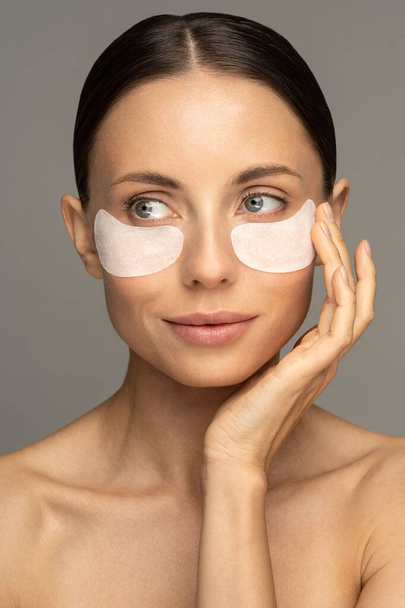 コラーゲンで強化されたハイドロゲルの眼の下回復パッチを適用する女性は、ビタミンEは、集中的な水分補給を提供し、老化の兆候を減少させ、眼のむくみを再利用するのに役立ちます。顔のスキンケアの美しさ.  - 写真・画像