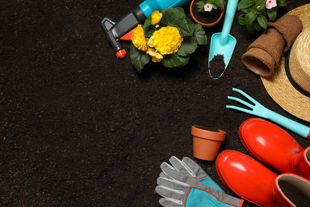Flat lay composition with gardening equipment and flowers on soil, space for text - Foto, immagini