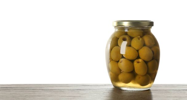 Glass jar of pickled olives on wooden table against white background. Space for text - Foto, afbeelding