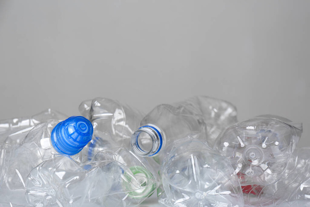 Many used plastic bottles against light background, space for text. Recycle concept - Foto, Imagen