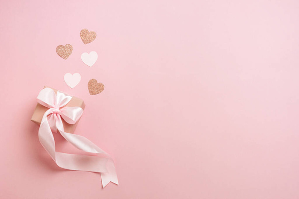 Подарочные коробки с розовой лентой и сердечки на пастельно-розовом фоне. День святого Валентина композиция с свободного пространства. Вид сверху, плоский. - Фото, изображение