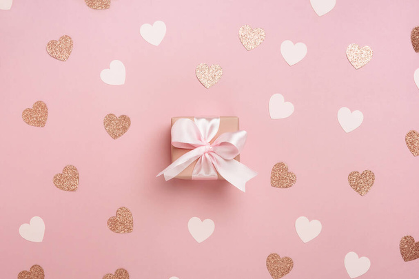 Ajándék doboz rózsaszín szalaggal pasztell rózsaszín háttér sok szív. Valentin napi kompozíció. Felülnézet, lapos fektetés. - Fotó, kép