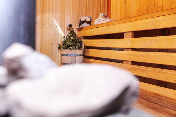 Interieur details Fins sauna stoombad met traditionele sauna accessoires wastafel berken bezem schepje vilten hoed handdoek. Traditioneel oud Russisch badhuis SPA Concept. Relax country dorpsbad concept. - Foto, afbeelding