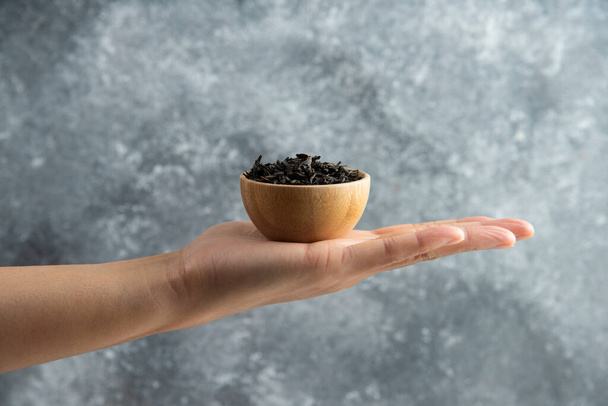 Hand holding a wooden bowl with dried loose teas - Φωτογραφία, εικόνα