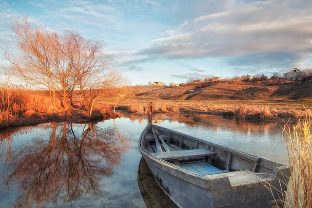 Stara łódź przy brzegu spokojnej rzeki Południowy Bug, Ukraina. Wschód słońca. W chmurach niebieskiego nieba. Widok panoramiczny. - Zdjęcie, obraz