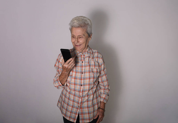 Großmutter im Gespräch mit ihrem Mobiltelefon. Technologie, Kommunikation und Konzept für ältere Menschen - Foto, Bild
