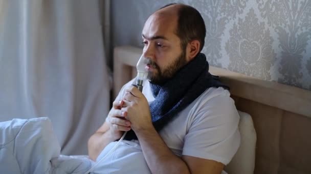 Koronavirüslü bir adam, grip, yatakta nebulizatör terapi solunum maskesi kullanıyor. Solunum tıbbı. Solunum astımı tedavisi. Bronşit, astım donanımı. Alternatif ev tedavileri. - Video, Çekim