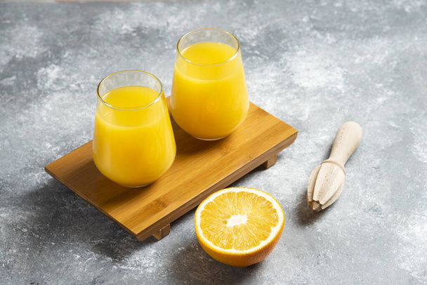 Vasos de zumo de naranja y un escarificador de madera - Foto, Imagen