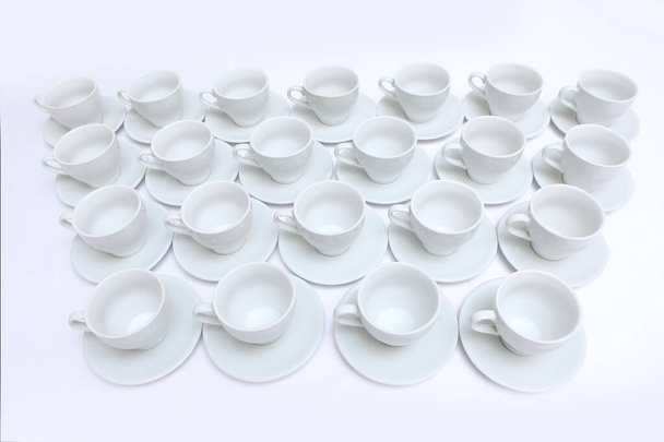 A large amount of white porcelain or ceramic crockery on the table. Tea pairs in abundance. Dishes for tea drinking. Catering or banquet concept. View from above. - Фото, изображение