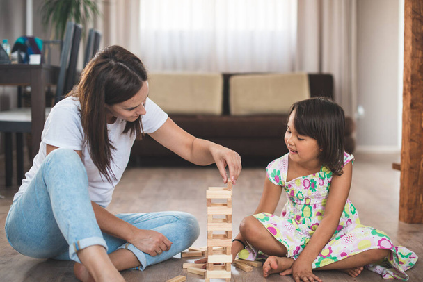 Young mother with her little daughter play game in wood block - Photo, Image