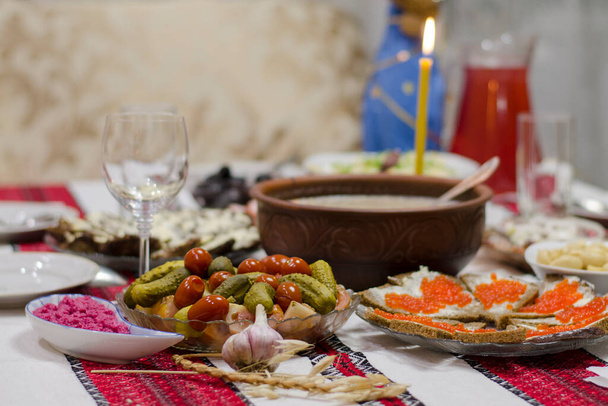 Традиционный рождественский стол в Украине. Двенадцать блюд без мяса: кутья, жареная рыба, сельдь, грибы, пончики и чеснок. - Фото, изображение