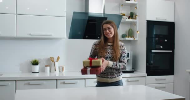 Happy woman dancing with gifts in her hands. Against the background of the kitchen. - Кадри, відео