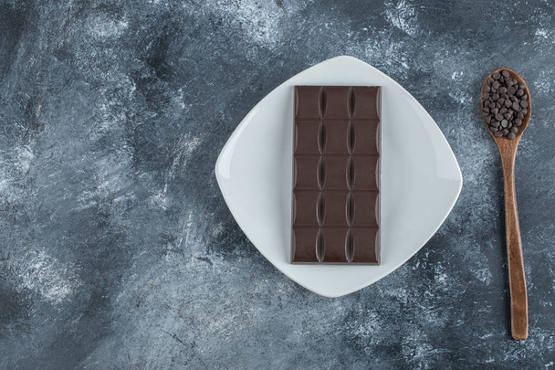 Bar of chocolate with chocolate chips on a marble background - Photo, Image