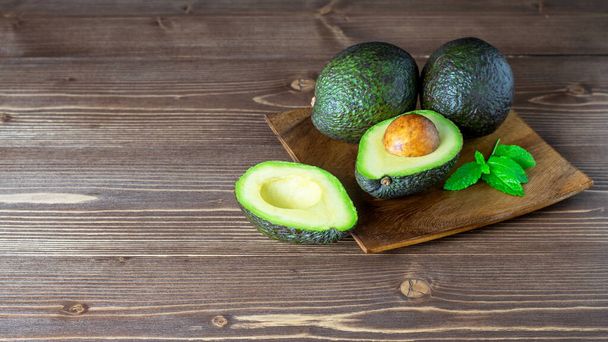 Group of fresh ripe whole and halved avocados on the wooden table. Healthy vegetarian eating. Banner photo, healthy concept.  - Photo, Image