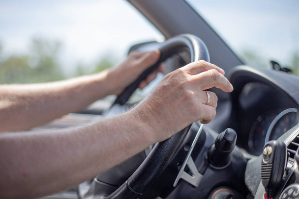 a man drives a car, hands lie on the steering wheel, car interior from the inside, selective focus - Foto, afbeelding