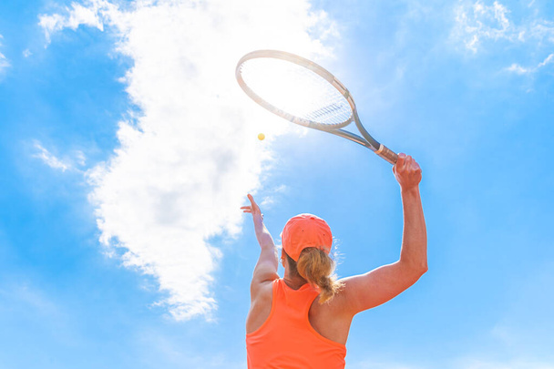 テニスはコートの若い女性によって提供されます。下からの眺め - 写真・画像