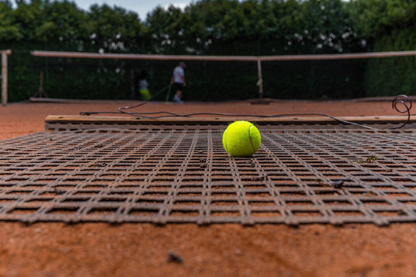 σκούπισμα πορτοκαλί πηλό σε ένα υπαίθριο γήπεδο τένις. - Φωτογραφία, εικόνα