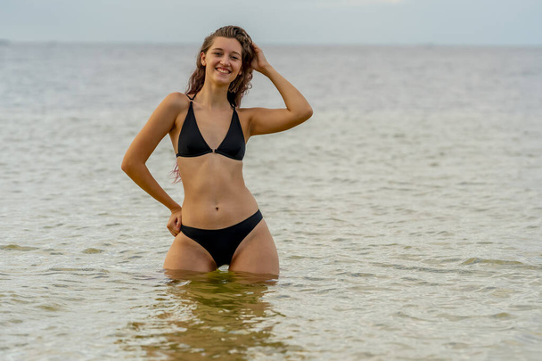 Una hermosa modelo de bikini morena disfruta del clima al aire libre en la playa - Foto, Imagen