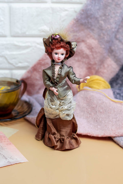 Écharpe tricotée avec une petite poupée en porcelaine de style anglais et thé vert au citron. fonds d'écran confortables, atmosphère à la maison, espace de copie - Photo, image