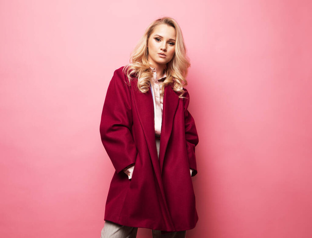 Fashion, people and lifestyle concept: Beautiful woman long blond curly hair wear cashmere coat over pink background - Photo, image