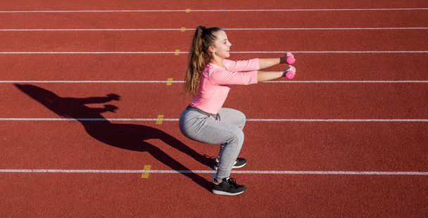meisje kind training sport met halters buiten op stadion arena, kracht - Foto, afbeelding