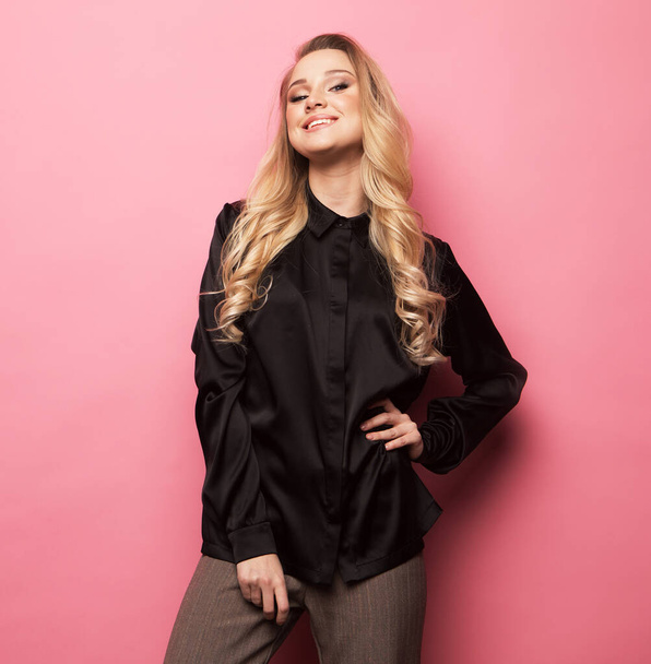 Beautiful blond woman pose for a photo in trendy clothes over pink background. Fashion and people concept. - Valokuva, kuva