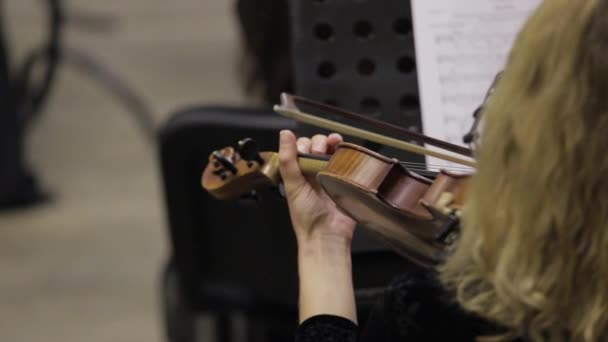 Cinematic close-up shot van vrouwelijke violist speelt violen tijdens een muzikaal concert op het klassieke theaterpodium met symfonieorkest op de achtergrond. - Video