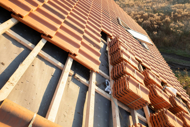 Stapels gele keramische dakpannen voor het afdekken van residentieel gebouwendak in aanbouw. - Foto, afbeelding