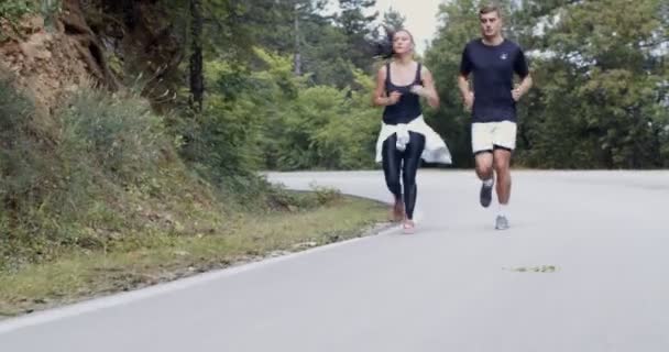 Coppia atletica che corre su una strada, natura in forma e concetto sano - Filmati, video