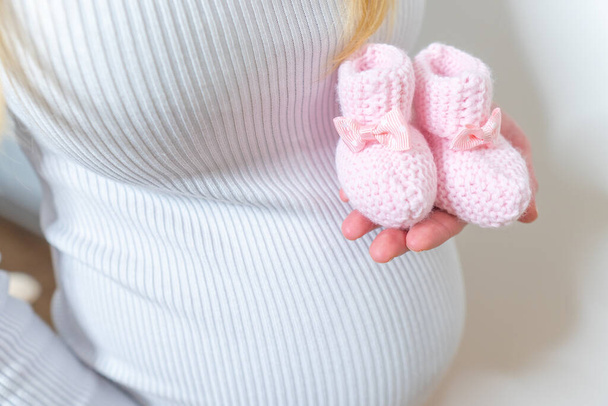 Małe buty dla nienarodzonego dziecka w brzuchu kobiety w ciąży - Zdjęcie, obraz