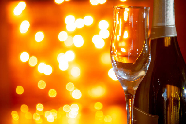 Пустой бокал шампанского и бутылка игристого вина или шампанского на фоне свечей в романтической обстановке. - Фото, изображение