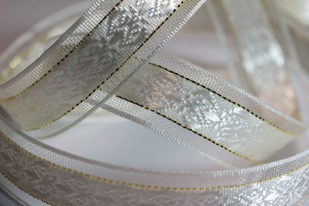 Полная рамка Макротекстура фона из мерцающей серебристо-белой парчовой ткани лента с золотым стежком, на белом фоне - Фото, изображение